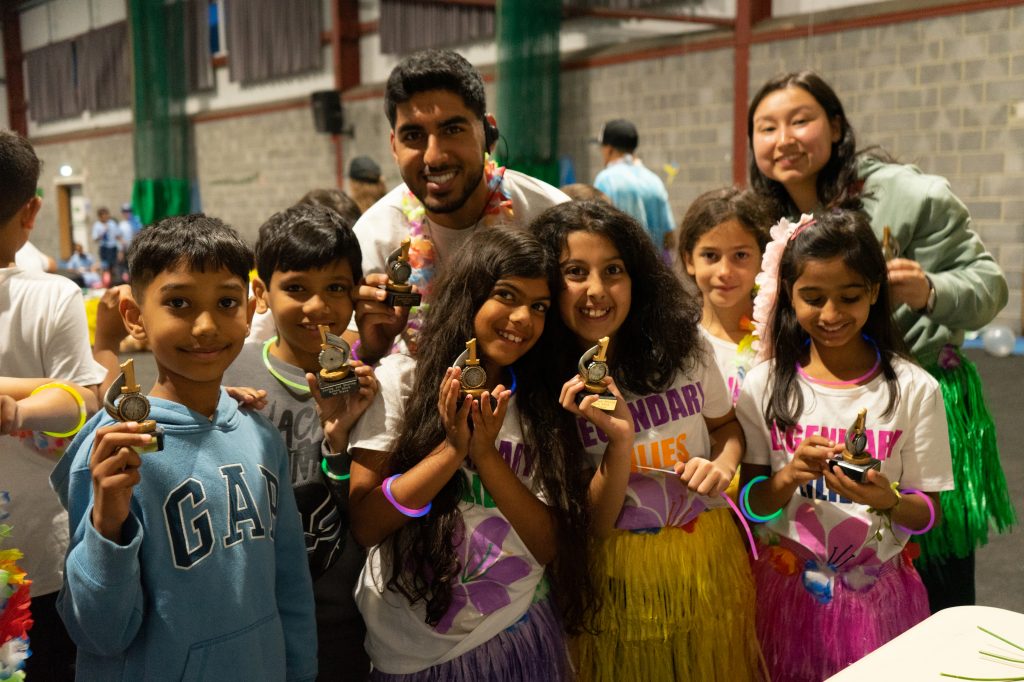 Group of campers and counsellors smiling holding a tropy